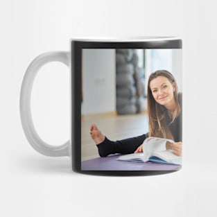 Young woman reading a yoga book Mug